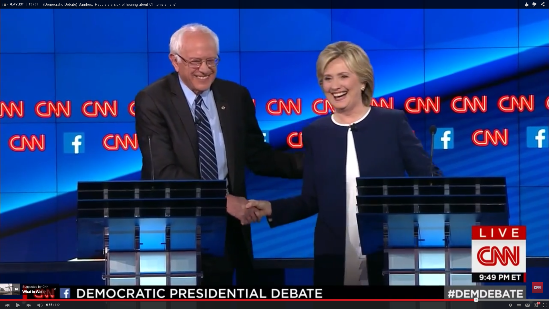 Sanders and Clinton smile and shake hands