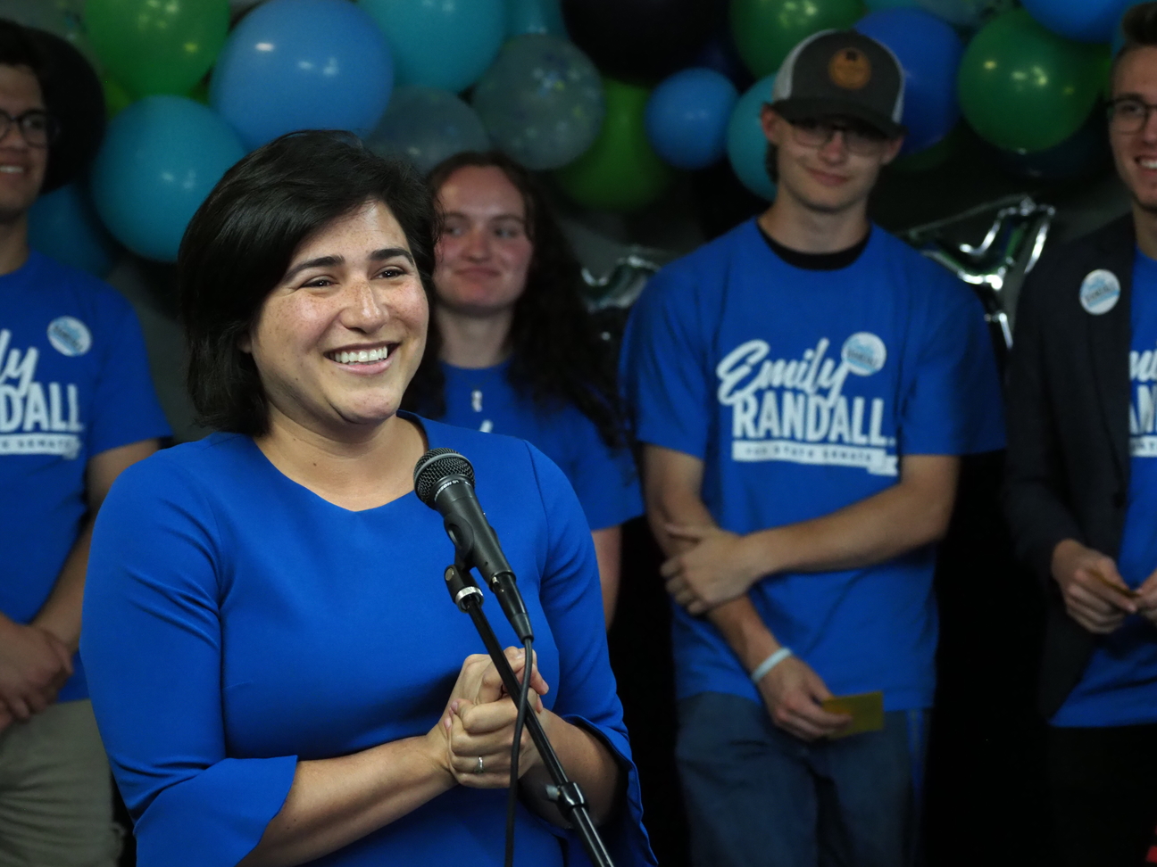 Emily Randall speaks at her campaign kickoff, flanked by her campaign team