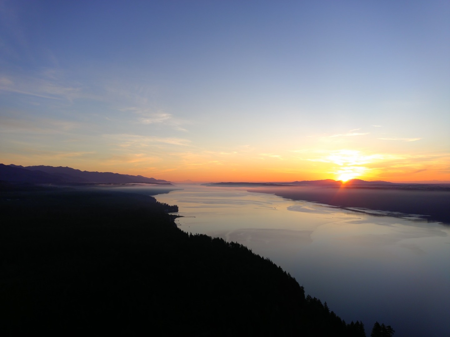 The sun rises over Hood Canal and the Olympics
