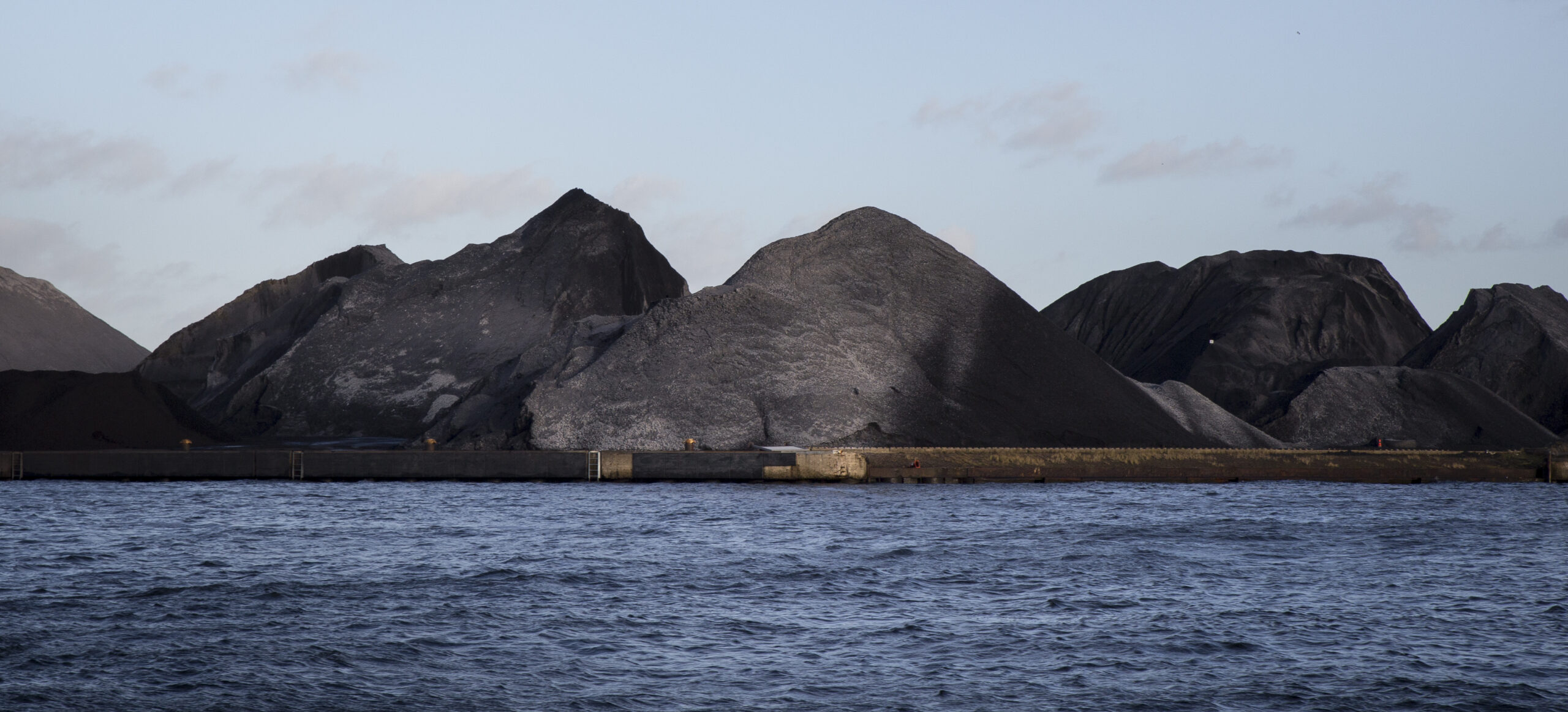 Piles of coal next to a shoreline
